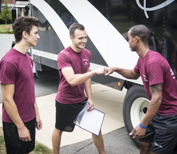Olympia movers carrying a pad-wrapped sofa