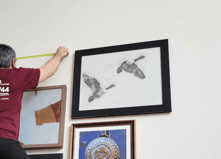 Installer measuring a wall to hang artwork
