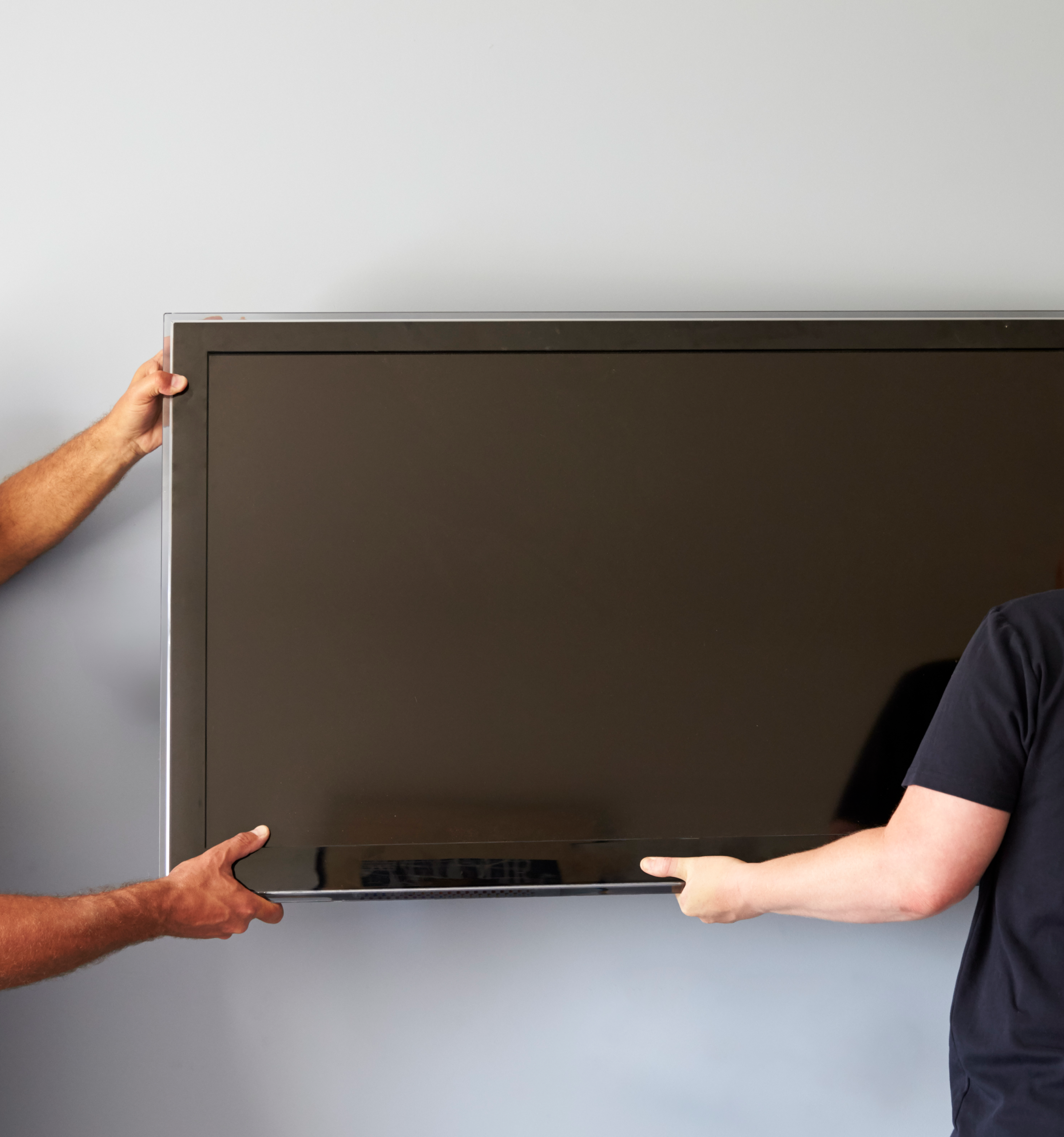 Two technicians mounting a flat-screen TV on a wall