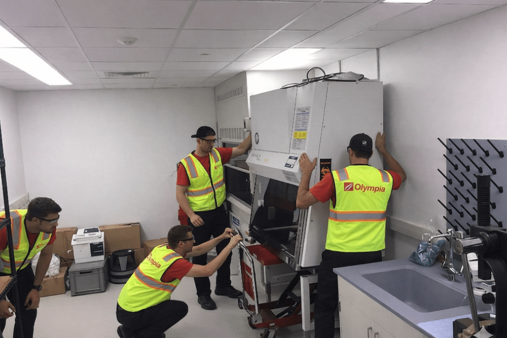 Olympia crew member in a safety vest moving laboratory equipment